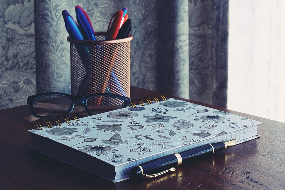 a neat desk setup with notebook, pen, and pen holder
