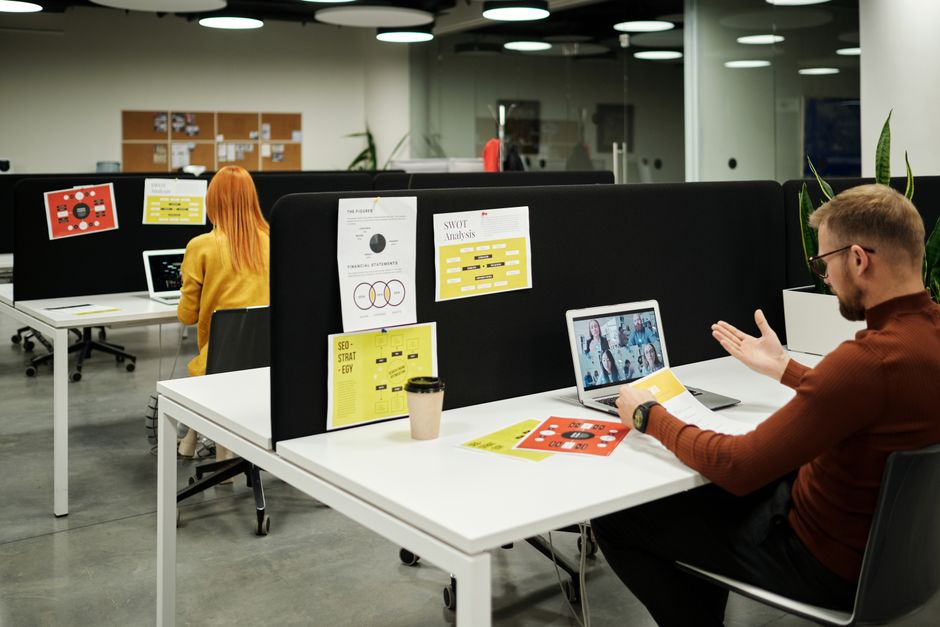 A man and a woman working remotely at desks in an office