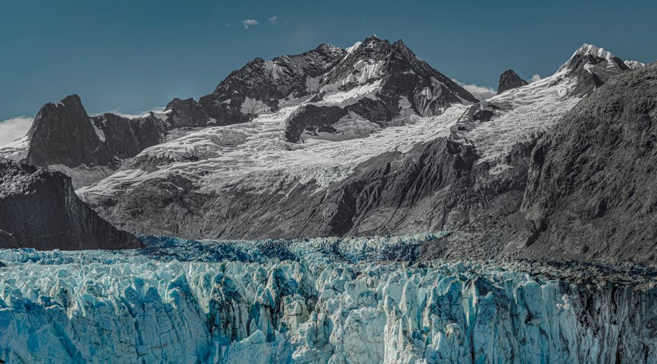 A landscape view of a high mountain range with melting glaciers and receding snow.