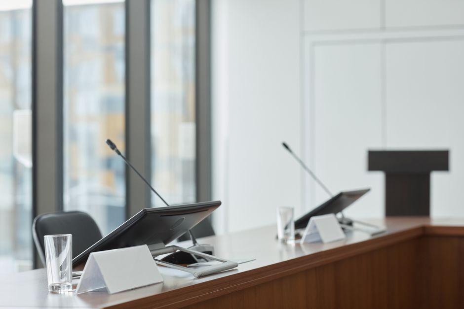Empty boardroom with microphones, monitors, and clear windows creating a professional setting.