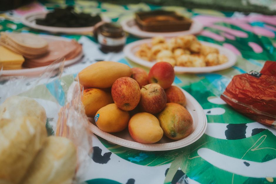 Vibrant picnic scene with fruits and snacks on a colorful blanket, perfect for a summer day outdoors.