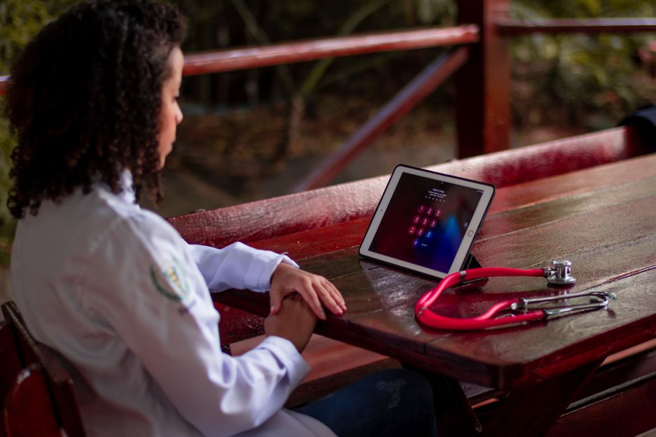 Female healthcare worker uses a tablet with stethoscope outdoors in São Paulo, Brazil.