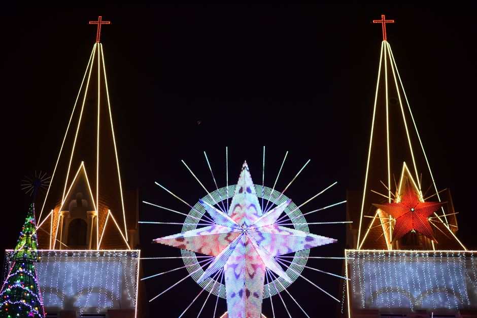 Night scene of a church adorned with bright festive decorations and an illuminated star.