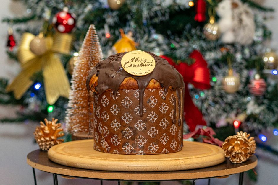 Delicious chocolate-glazed panettone with Christmas decorations in the background.