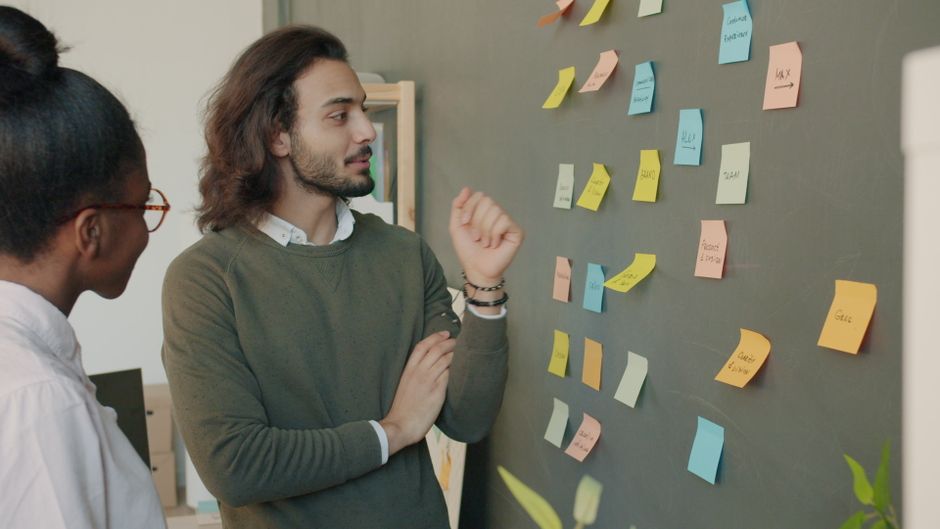 Colleagues engage in active brainstorming session using colorful sticky notes.
