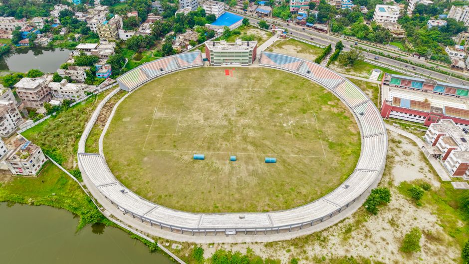 A wide aerial shot of a large empty stadium surrounded by residential buildings.