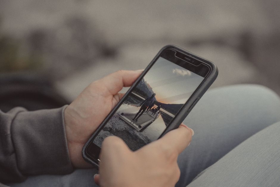 Close-up of hands holding a smartphone showing a mountain scene, captured outdoors in Banff.
