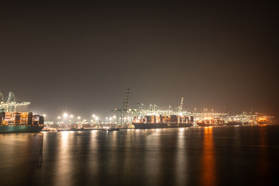 Luminous night view of a bustling industrial port with cargo ships.