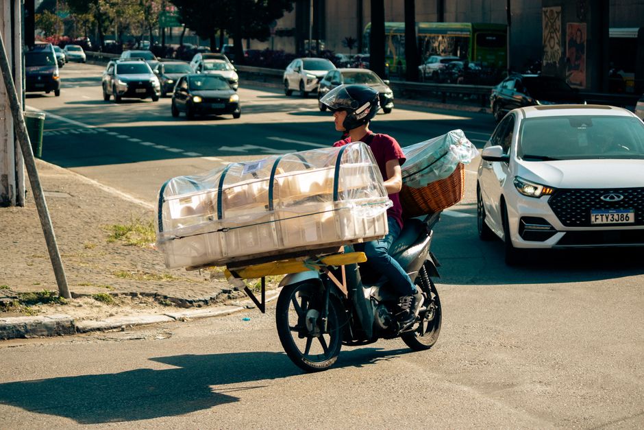 Motorcyclist transporting large packages through urban traffic, showcasing a unique delivery method.