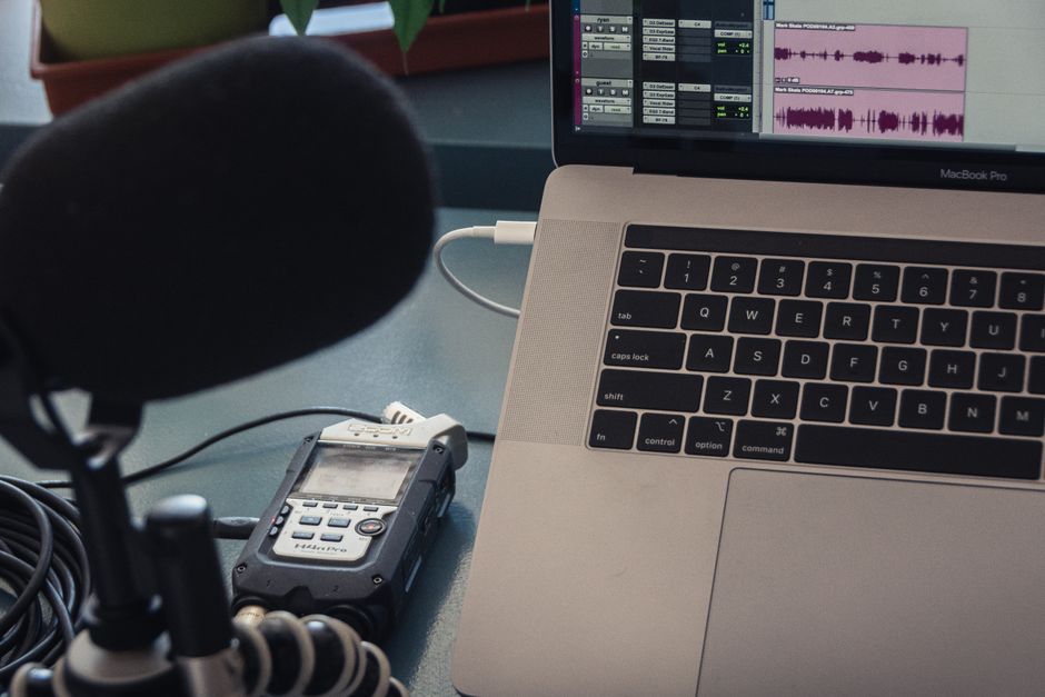 Microphone and laptop setup for audio recording in a studio environment.