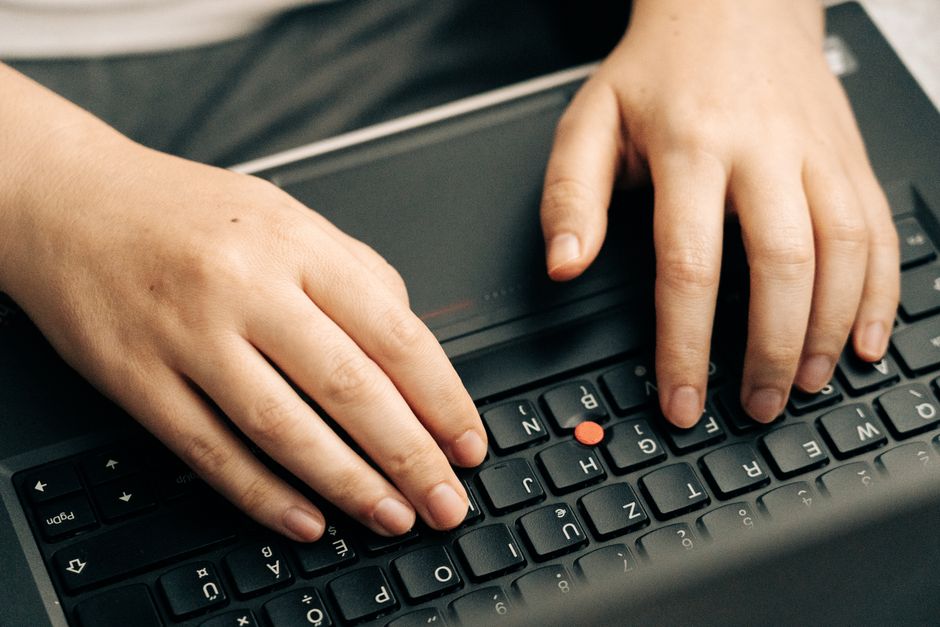 Close-up of hands typing on a black laptop's keyboard emphasizing productivity.