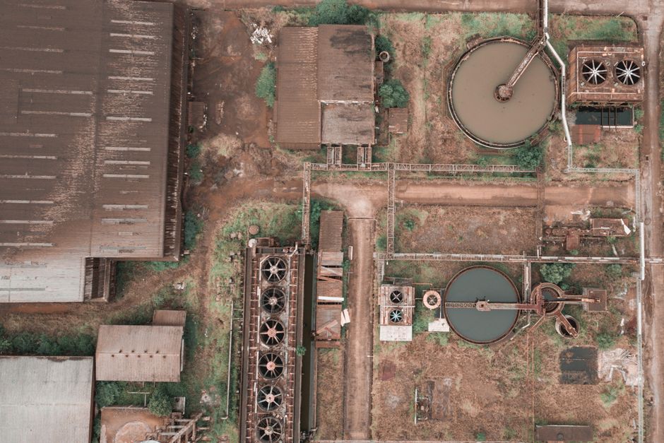 Aerial view of shabby dirty buildings and basins in abandoned industrial district in daytime