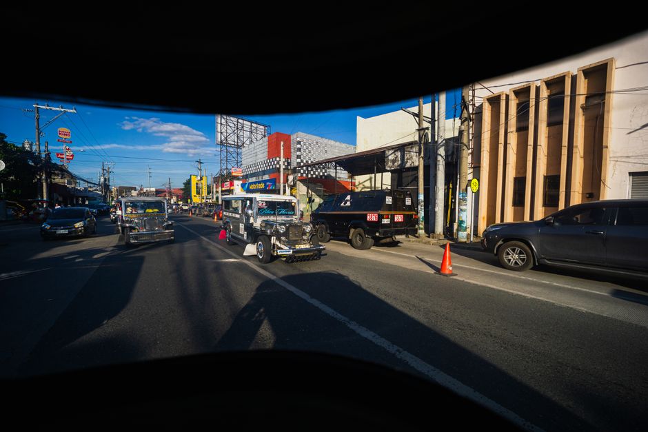 Dynamic view of jeepneys on a bustling city street with clear skies.