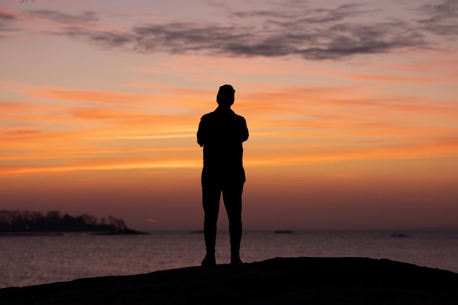 A person silhouettes against a vibrant sunrise at Cove Island Park, Stamford.