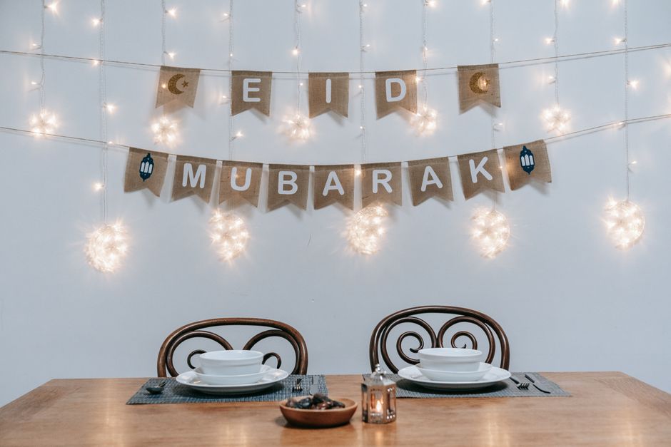 A beautifully arranged dining table with Eid Mubarak decorations and string lights, creating a festive ambiance.