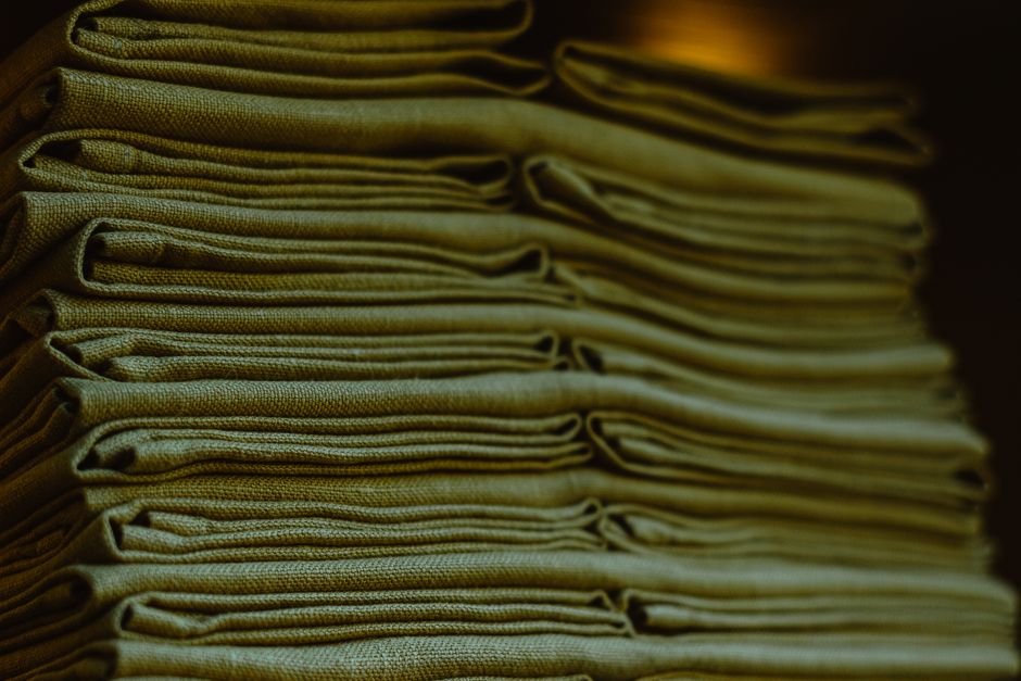 Close-up of a stack of neatly folded green linens highlighting their texture and neatness.