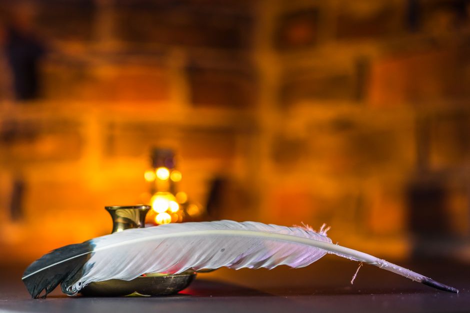 A serene close-up of a vintage feather quill on a brass ink pot, evoking nostalgia.