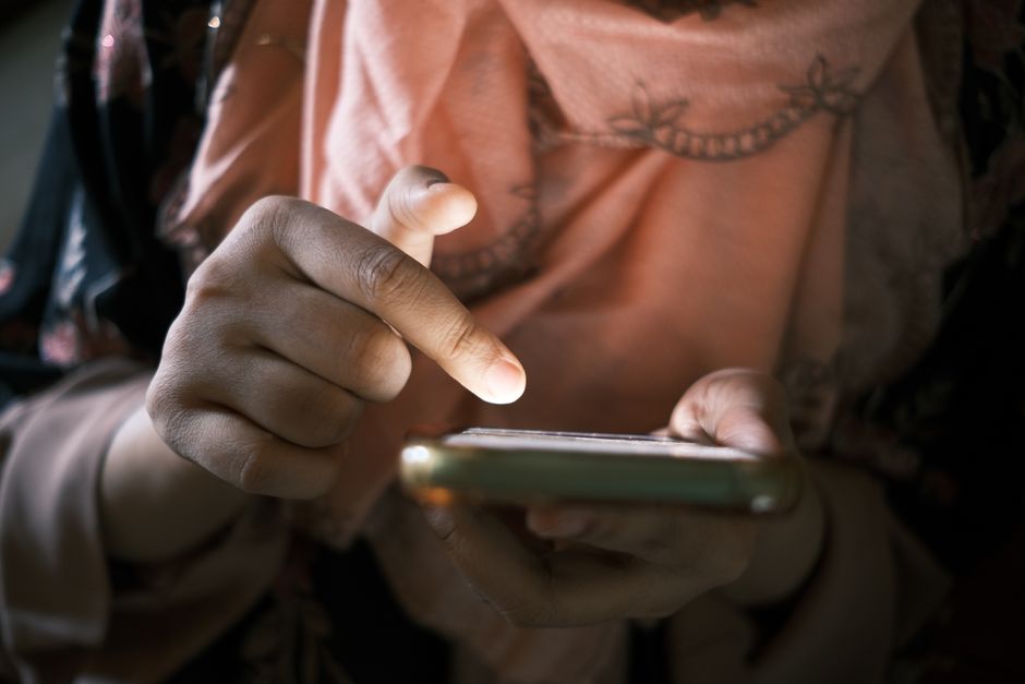 Close-up of hands using a smartphone indoors, highlighting touch technology.
