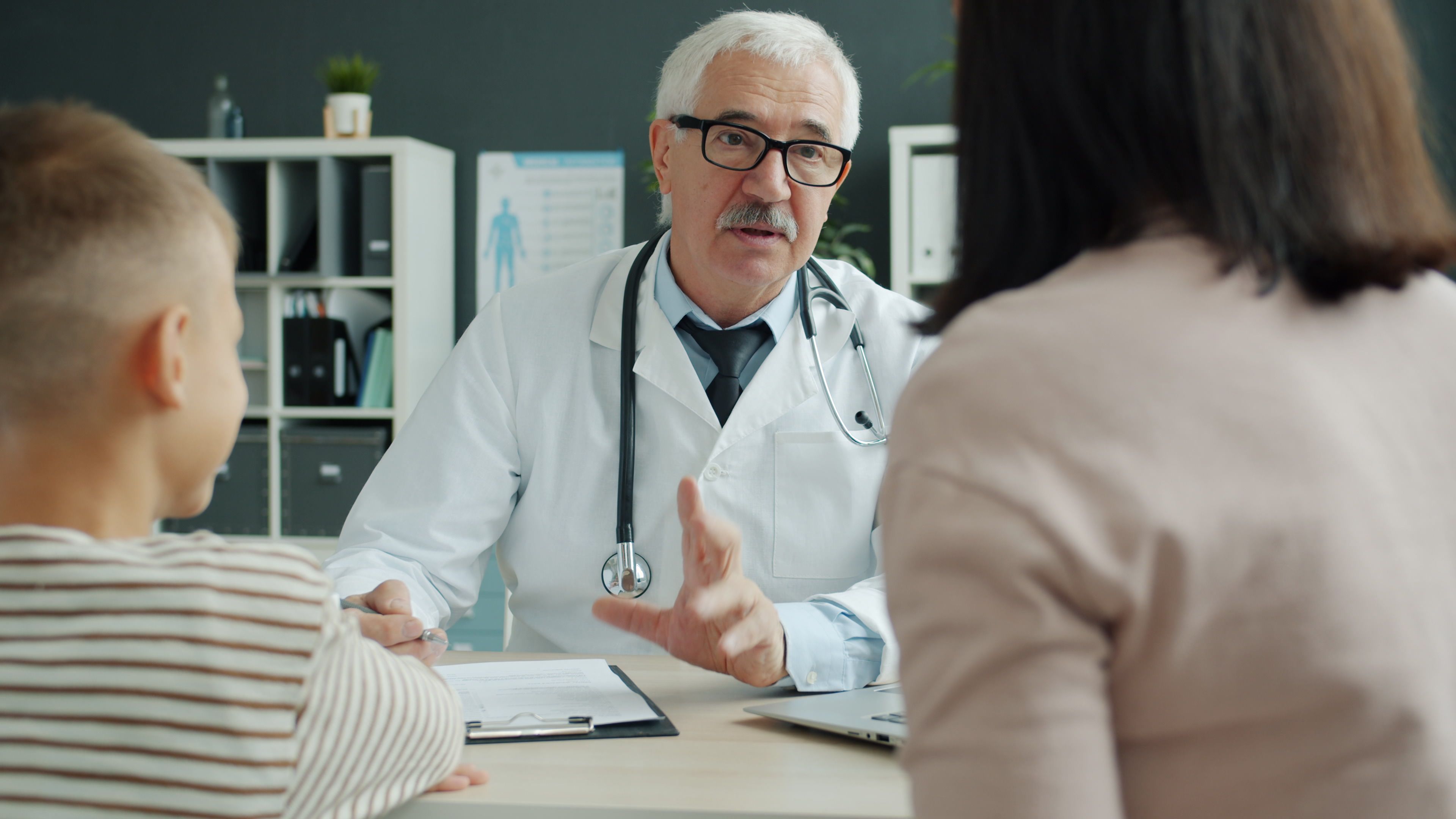A doctor discussing a patient's health with family members during a medical consultation in a professional healthcare setting.
