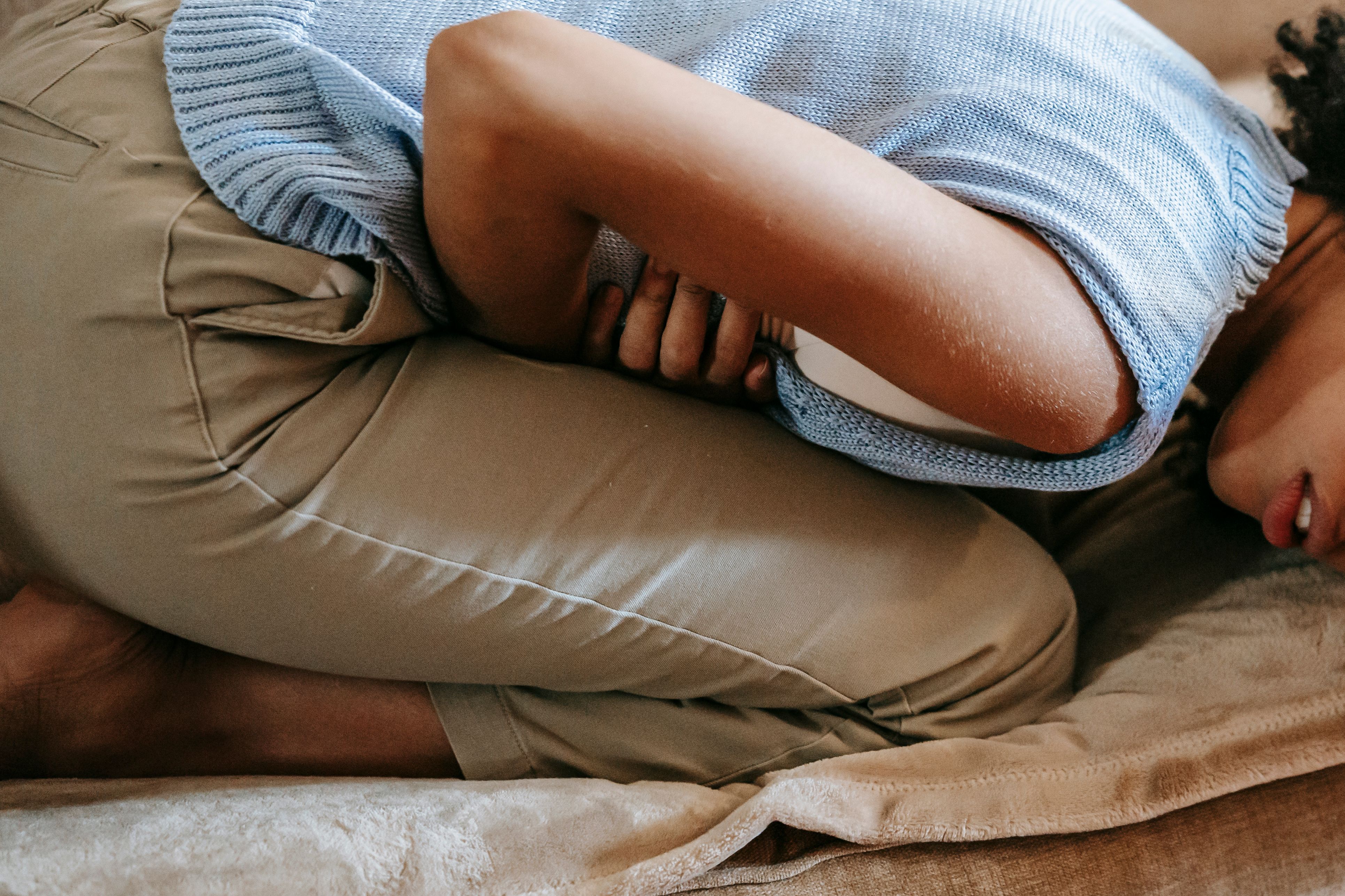 Woman Experiencing Menstrual Cramps A woman experiencing abdominal pain, representing menstrual cramps and the discomfort many women face during their periods.