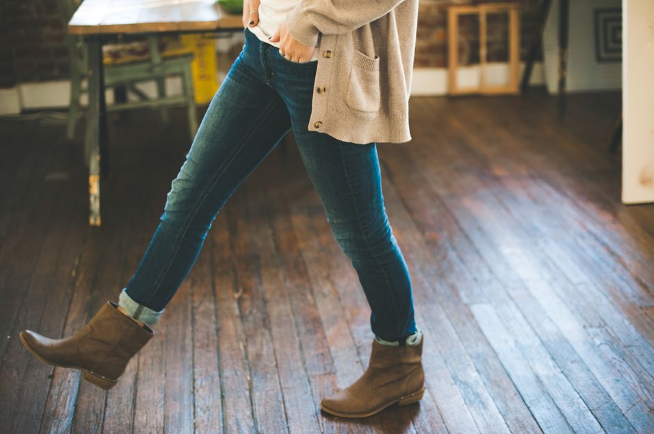 Woman in casual boots and denim stepping confidently indoors.