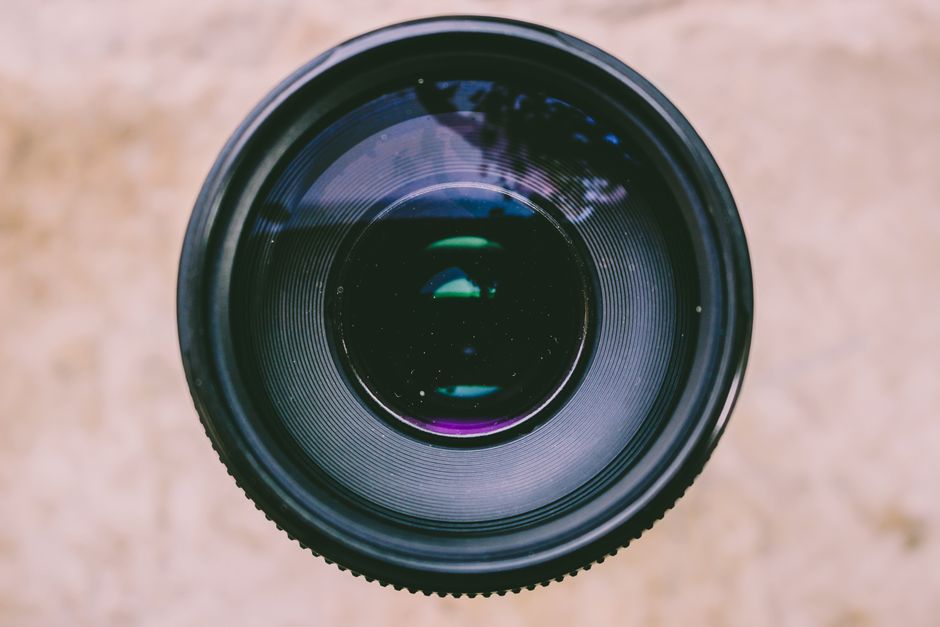 Detailed view of a camera lens capturing light and reflections, showcasing optical technology.