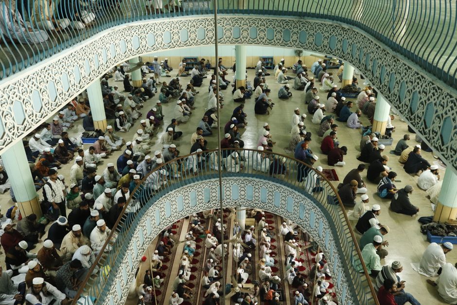 A large congregation gathers inside an intricately designed mosque, showcasing unity during prayer.