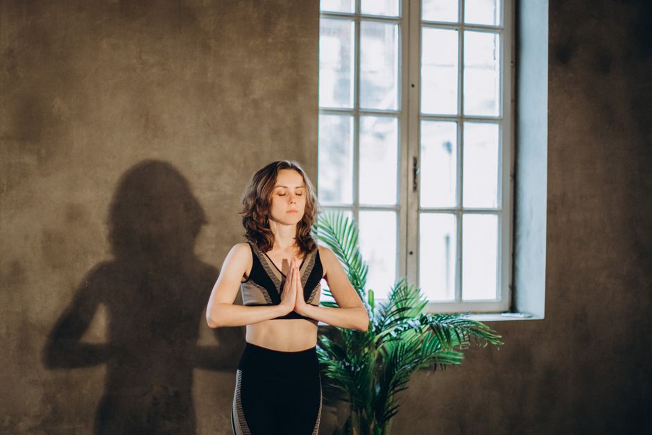 A calm woman practicing yoga in a serene indoor setting, focusing on mindfulness and relaxation.