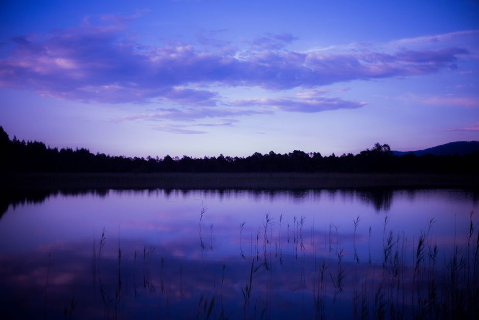 A serene lake reflecting the vibrant twilight sky, offering a peaceful and calming scene.