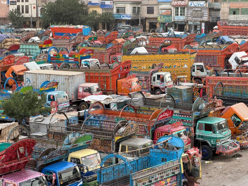 A vivid display of colorful decorated trucks in a bustling market, showcasing traditional Pakistani art.