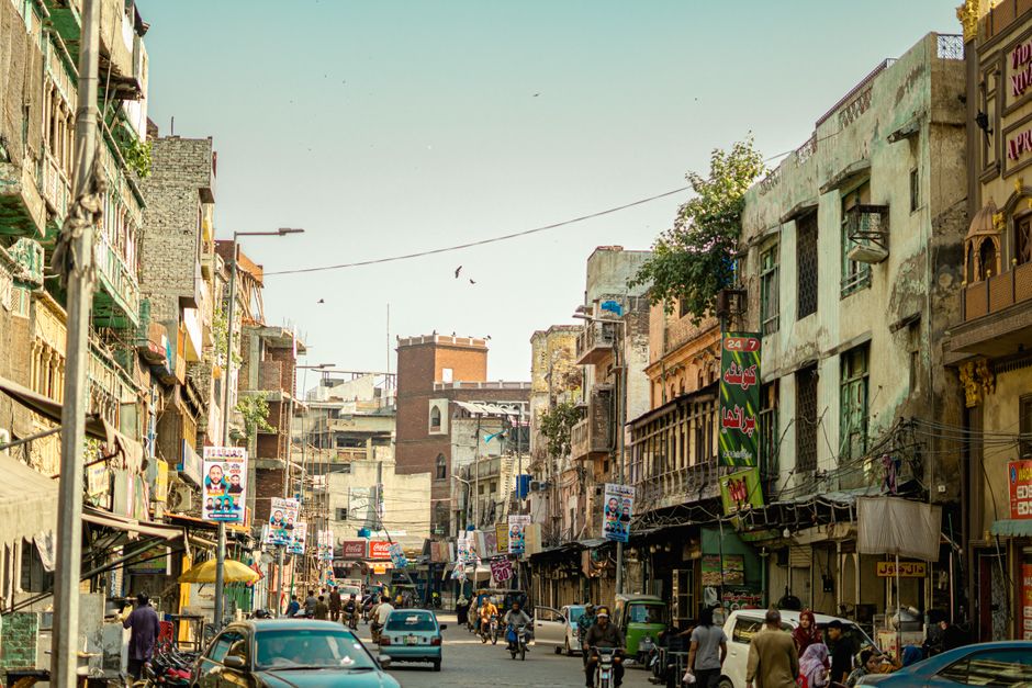 Vibrant street life in Lahore with people, vehicles, and classic architecture under a clear sky.