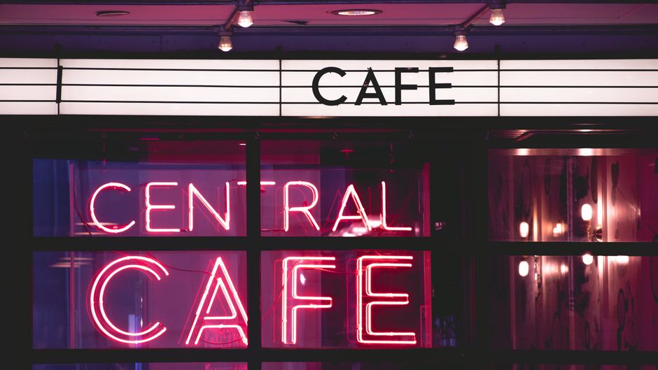 Vibrant neon 'Central Cafe' sign at night, creating an urban atmosphere.