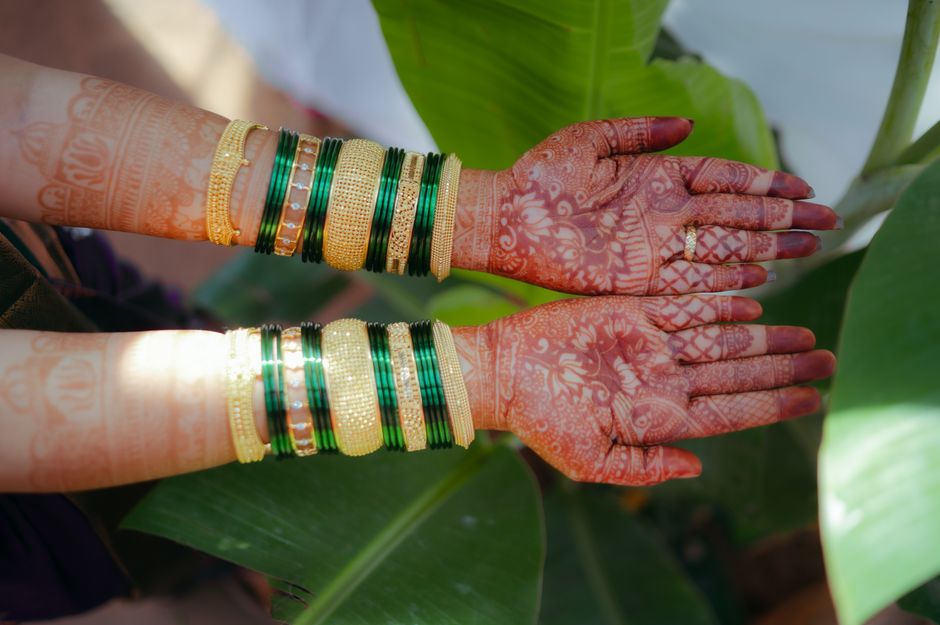 An exquisite display of bridal mehndi adorned with gold and green bangles, capturing traditional beauty.