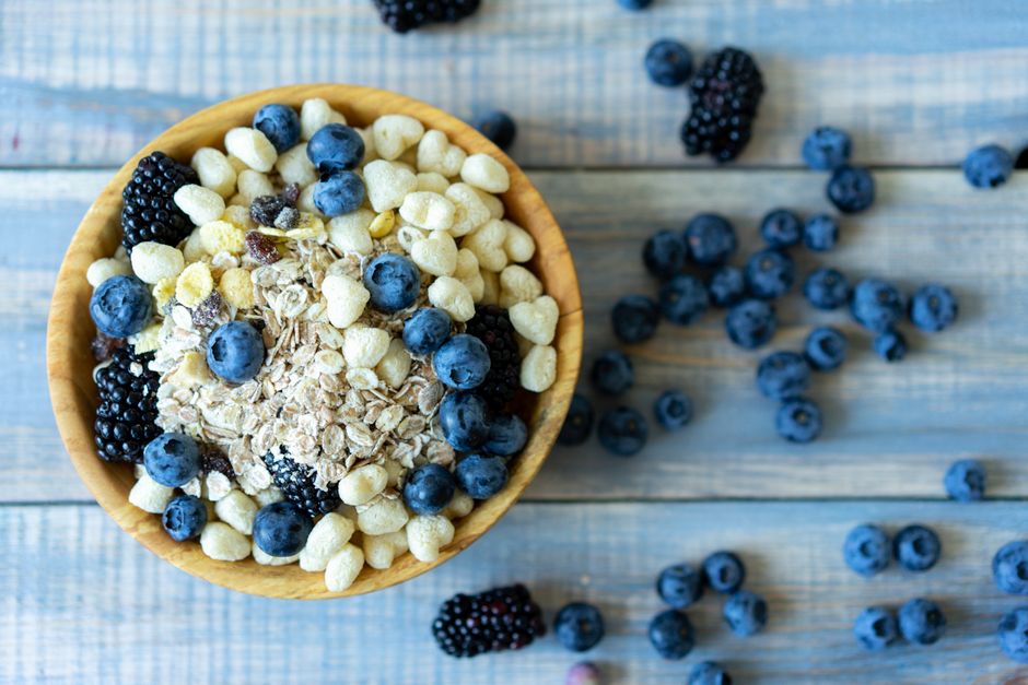 Top view of a nutritious breakfast bowl with blueberries, blackberries, and cereal on a rustic wooden table.