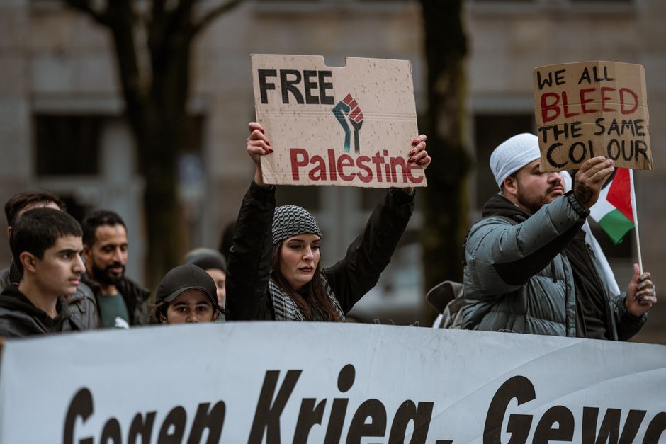 Participants in a rally holding signs promoting peace and equality.