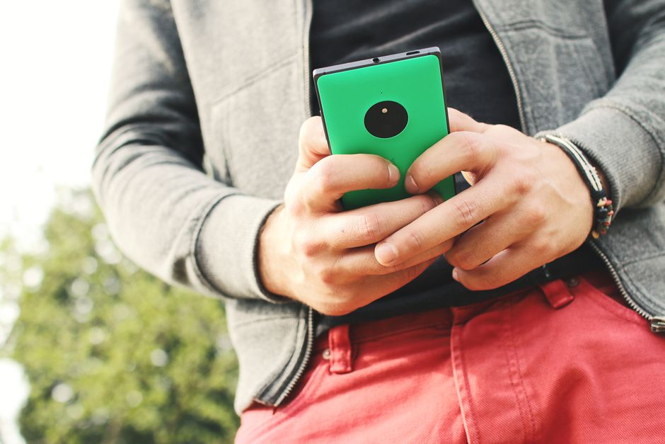 A person wearing casual clothes outdoor holding a smartphone, emphasizing a connected lifestyle.