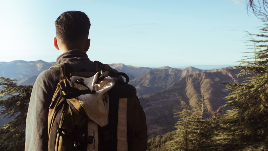 A solitary hiker with a backpack admires the stunning mountain landscape in Algeria, capturing a moment of exploration and tranquility.