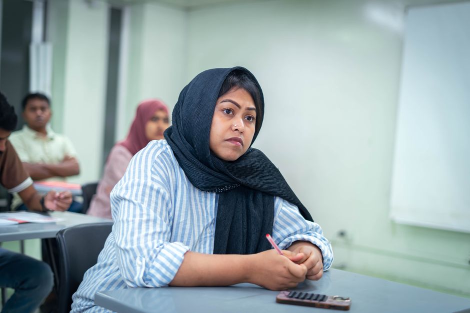 A student attentively taking notes in an educational setting, showcasing active learning.