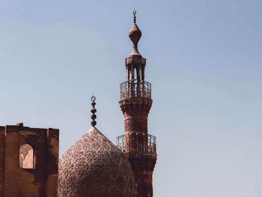 Detailed view of a mosque's minaret and dome against a clear sky in Cairo, Egypt.