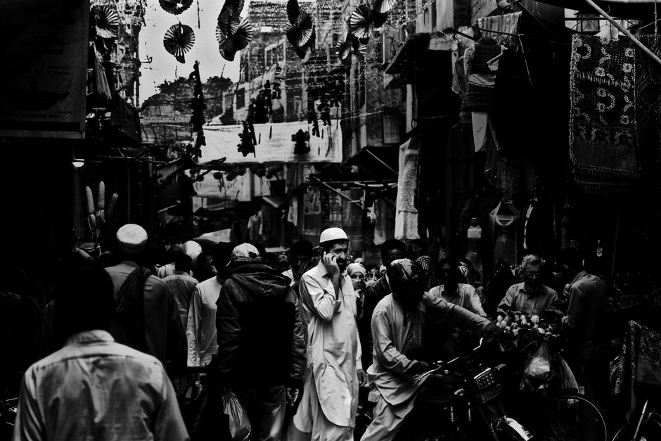 Monochrome image of a busy street market, featuring a crowd of people in an urban setting.