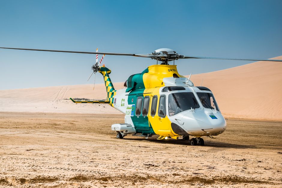 A medical helicopter parked on the sandy desert in Doha, Qatar, ready for emergency service.