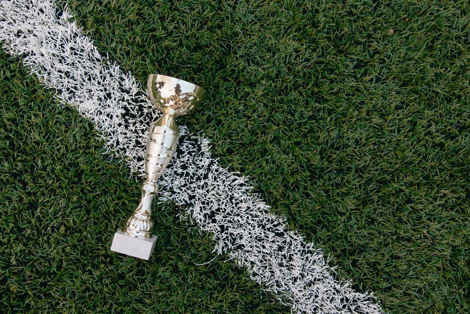 A gold trophy placed on green grass beside a white field line.