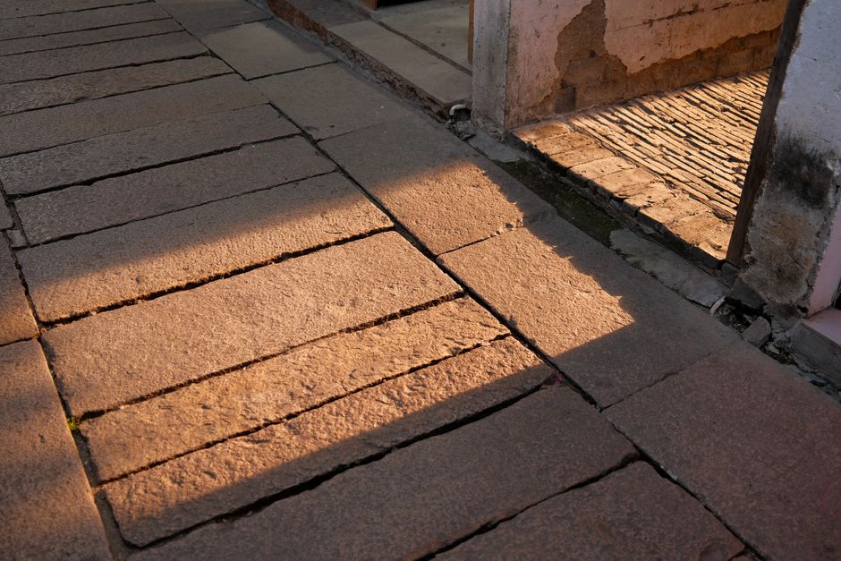 Sunlit stone pathway in Suzhou, China, casting dramatic shadows in the evening light.