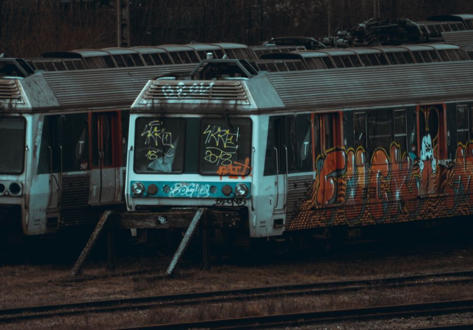 Abandoned trains with graffiti in a railway yard, showcasing urban decay.