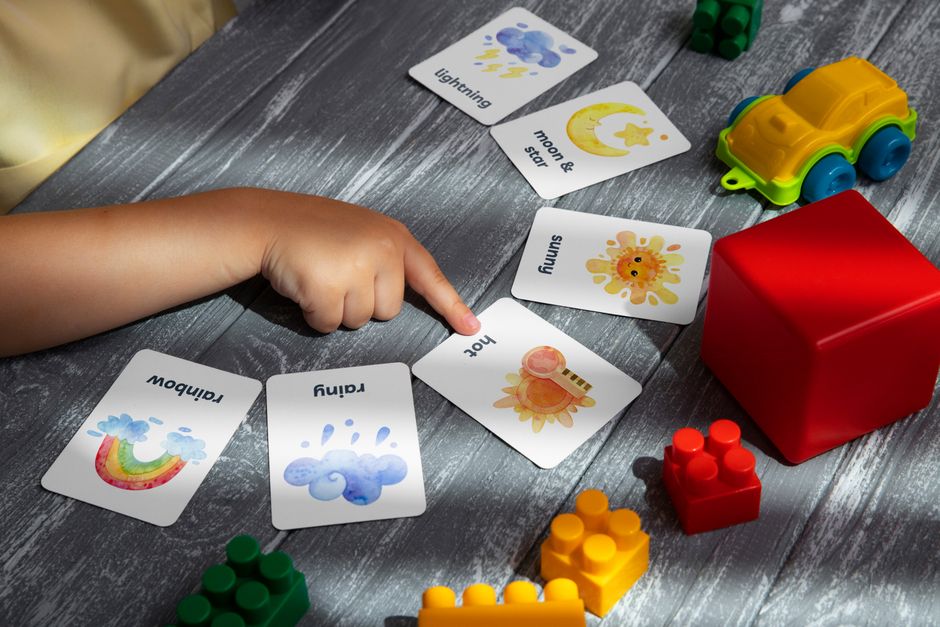Close-up of a child pointing at colorful educational flashcards and toys, promoting learning and creativity.