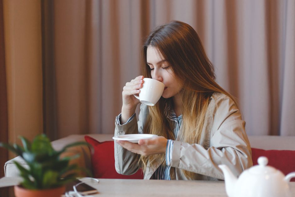 A woman savoring a warm drink in a cozy indoor setting, depicting relaxation.