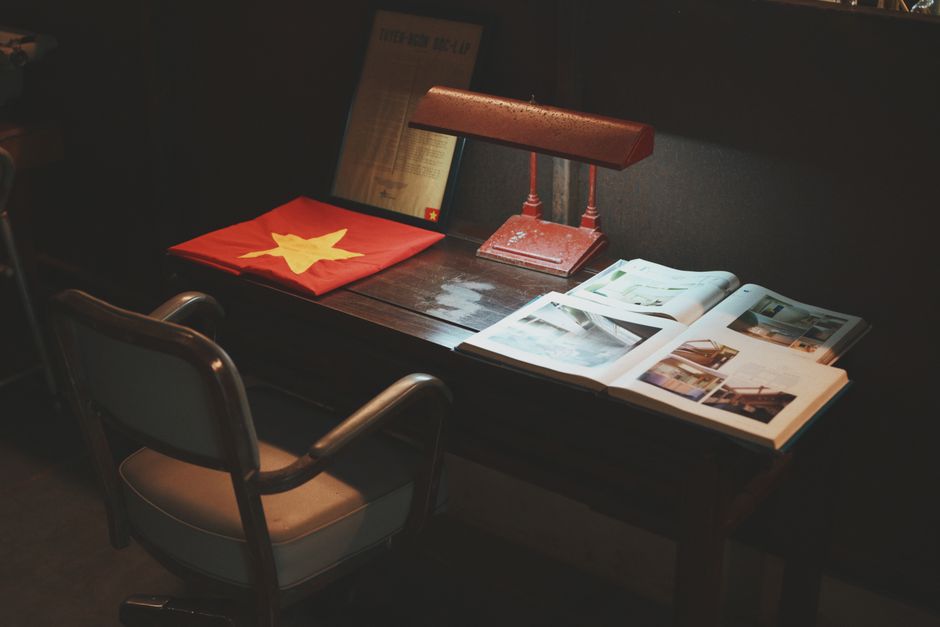 A rustic desk setup featuring a bright flag, vintage lamp, and open books, creating a nostalgic study atmosphere.