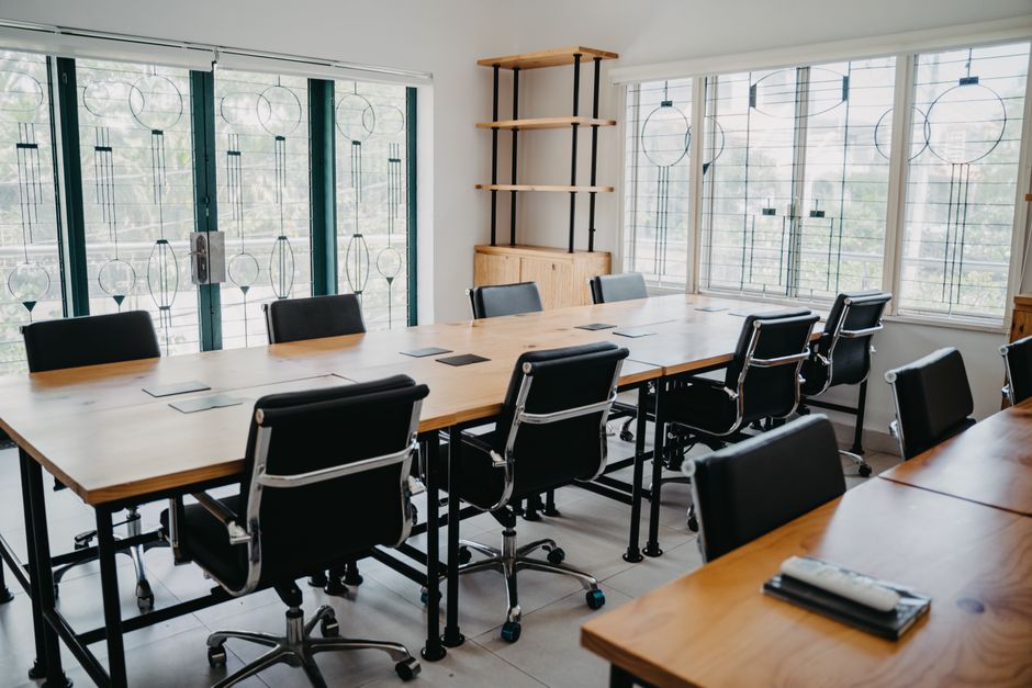 Spacious modern office conference room with black chairs and wooden tables.
