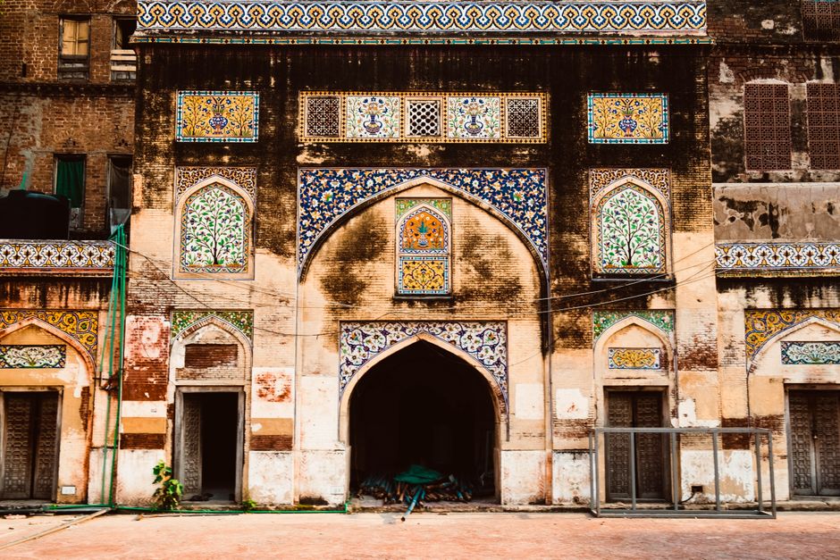 Ornate facade of ancient building in Lahore with colorful mosaic and arched entrance.