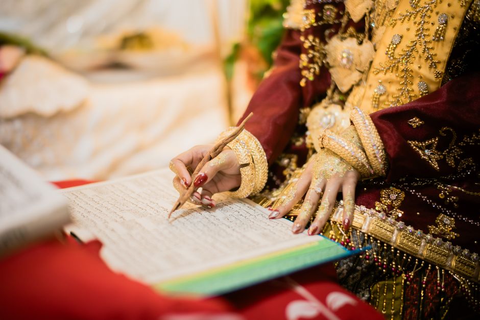 Close-up of a woman's hand writing in a traditional ceremony in Kendari.